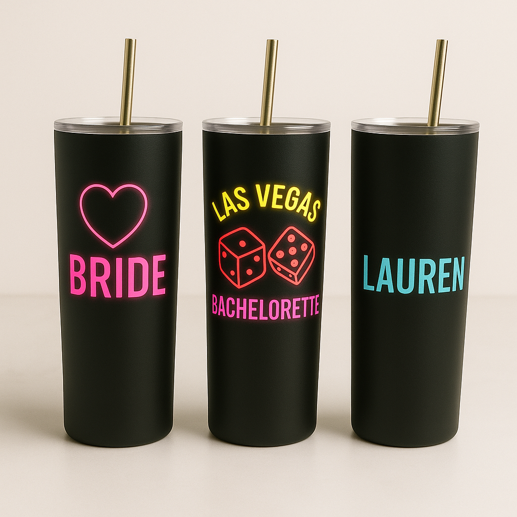 Three black tumblers with colorful text and designs on a beige background
