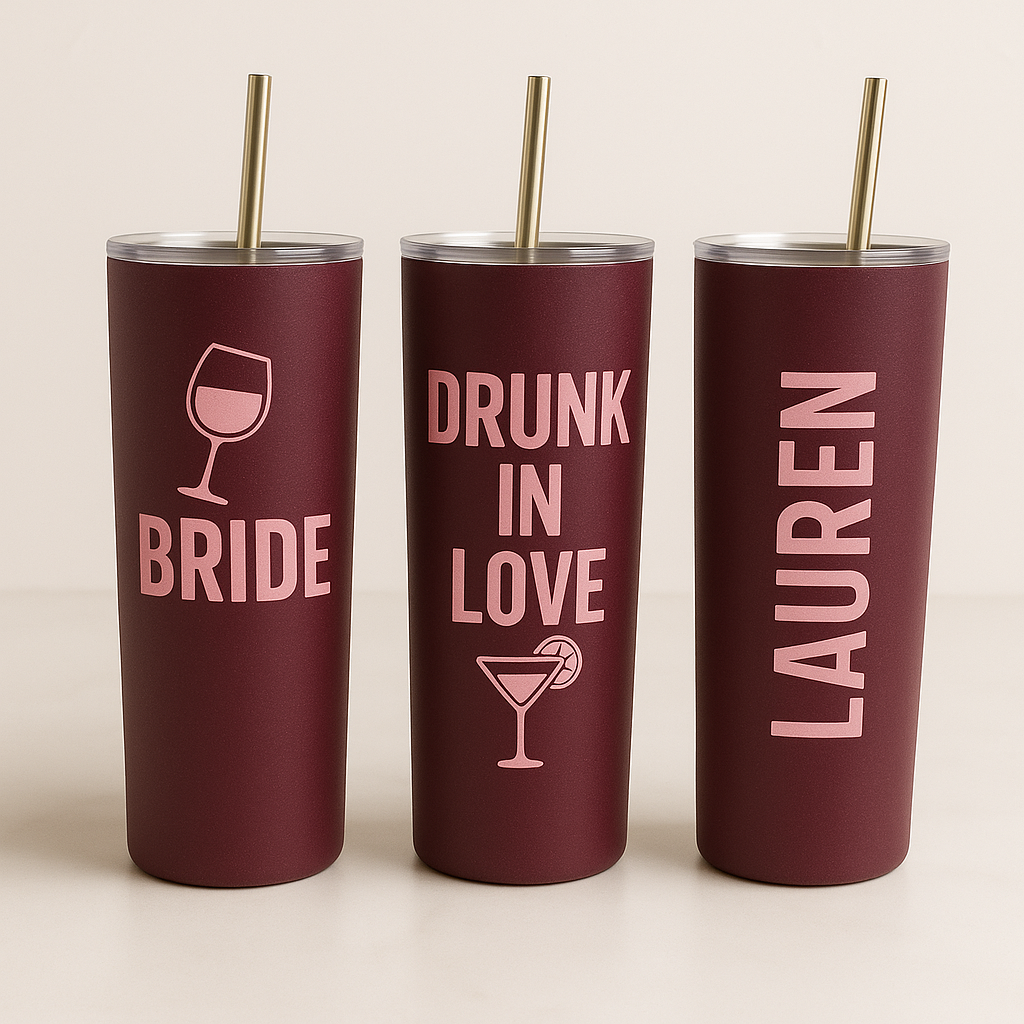 Three maroon tumblers with pink text and graphics on a beige background